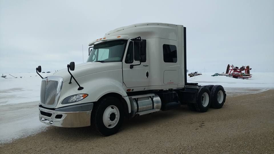 A white semi truck is parked on a snowy beach.