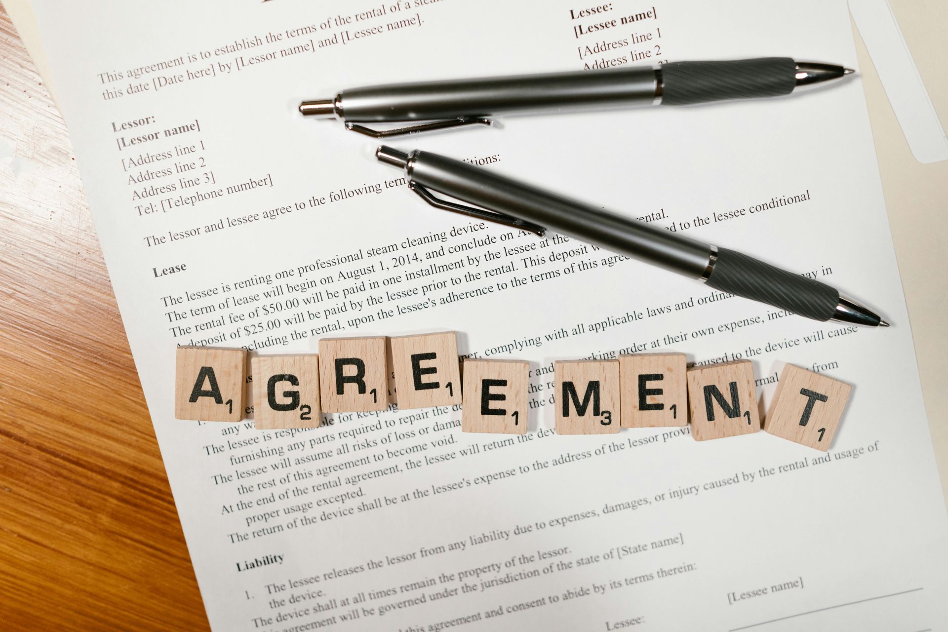 Agreement document with pens and scrabble tiles spelling 