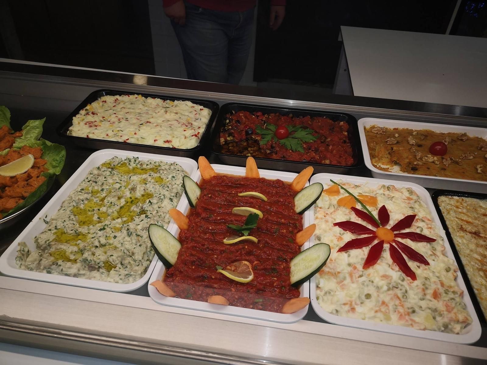 Esposizione di vari piatti colorati preparati in un ambiente da ristorante.