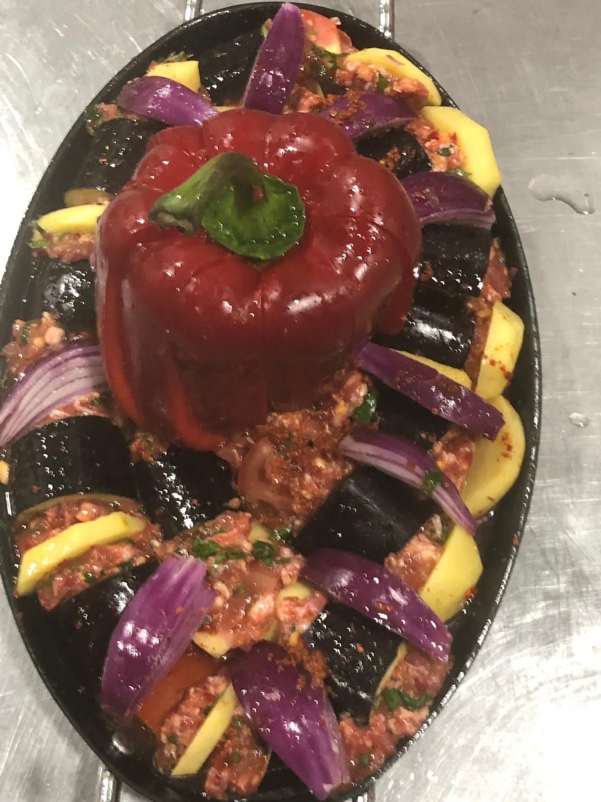 Piatto ovale con melanzane, peperoni e cipolle ripieni in salsa rossa.