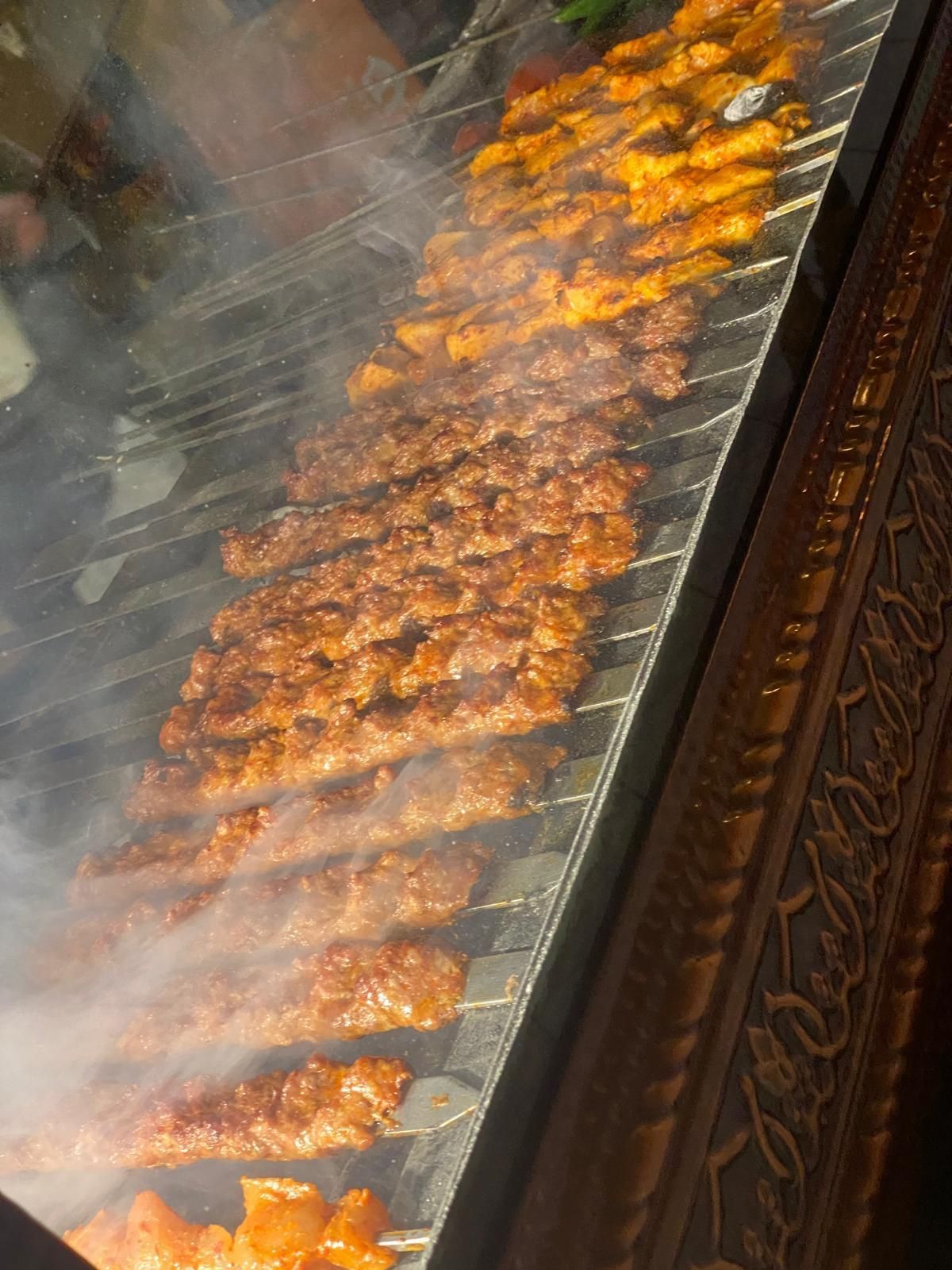 Spiedini infilzati e cotti su una griglia di metallo, con il vapore che fuoriesce.