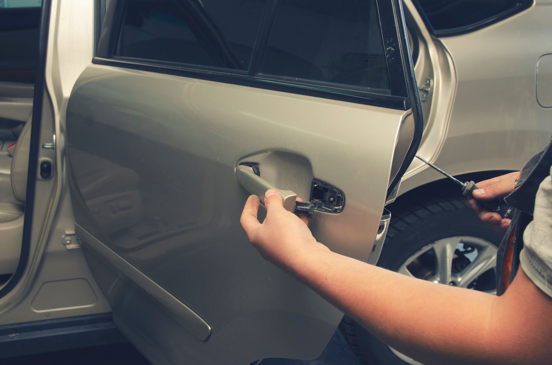 A car mechanic repairs a car door with tools.