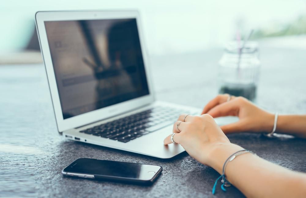 A Woman is Typing on a Laptop Next to a Cell Phone — Leading Edge Computers in Forster, NSW