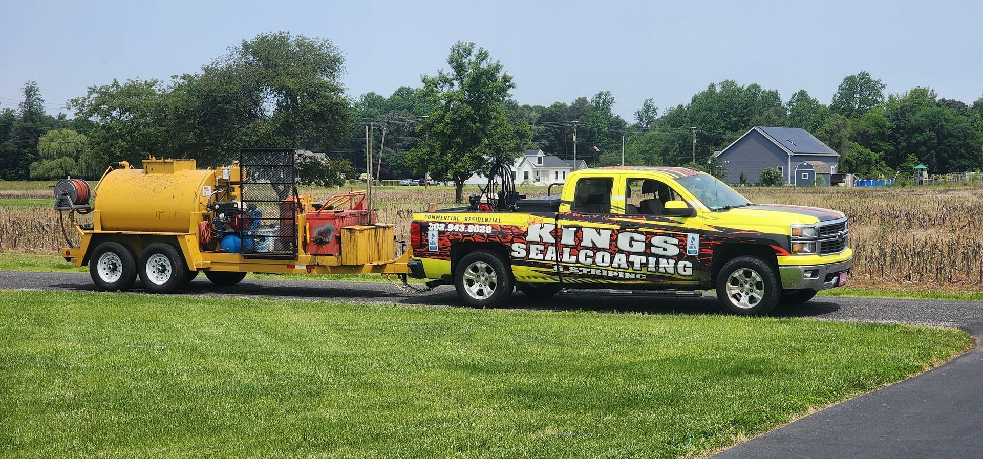 Yellow truck towing a yellow trailer with equipment, on a grassy area.
