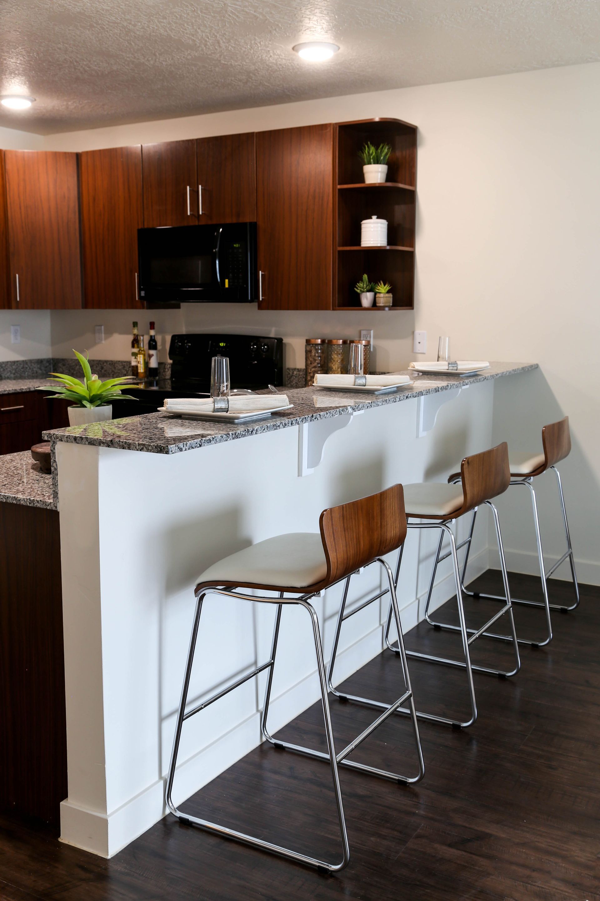 A kitchen with a bar and stools in front of it