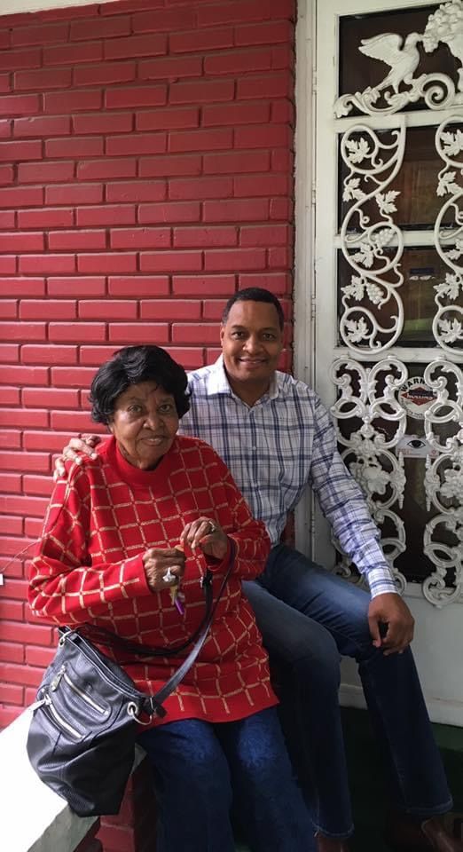 A man and a woman are posing for a picture in front of a red brick wall.