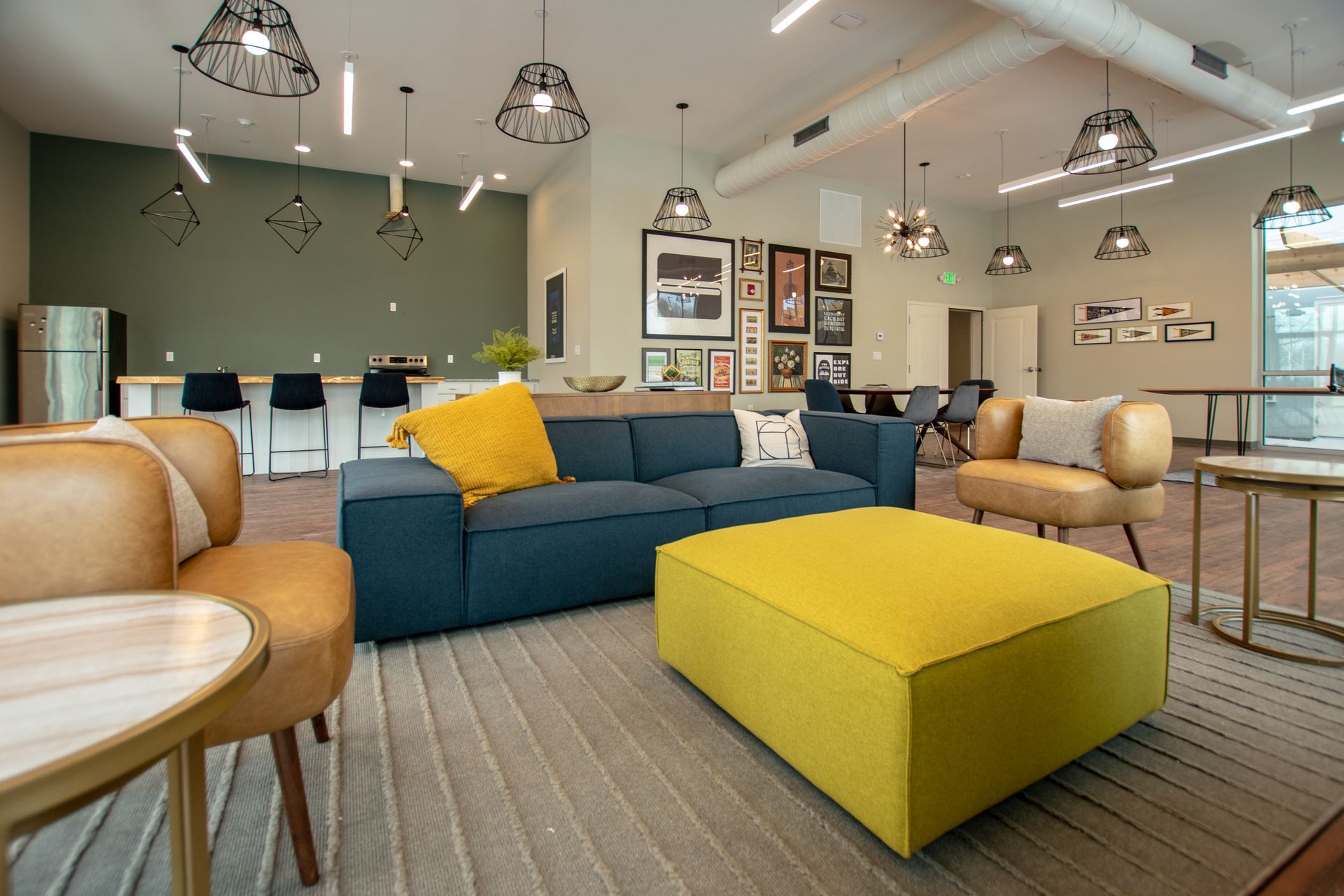 A living room with a blue couch and a yellow ottoman