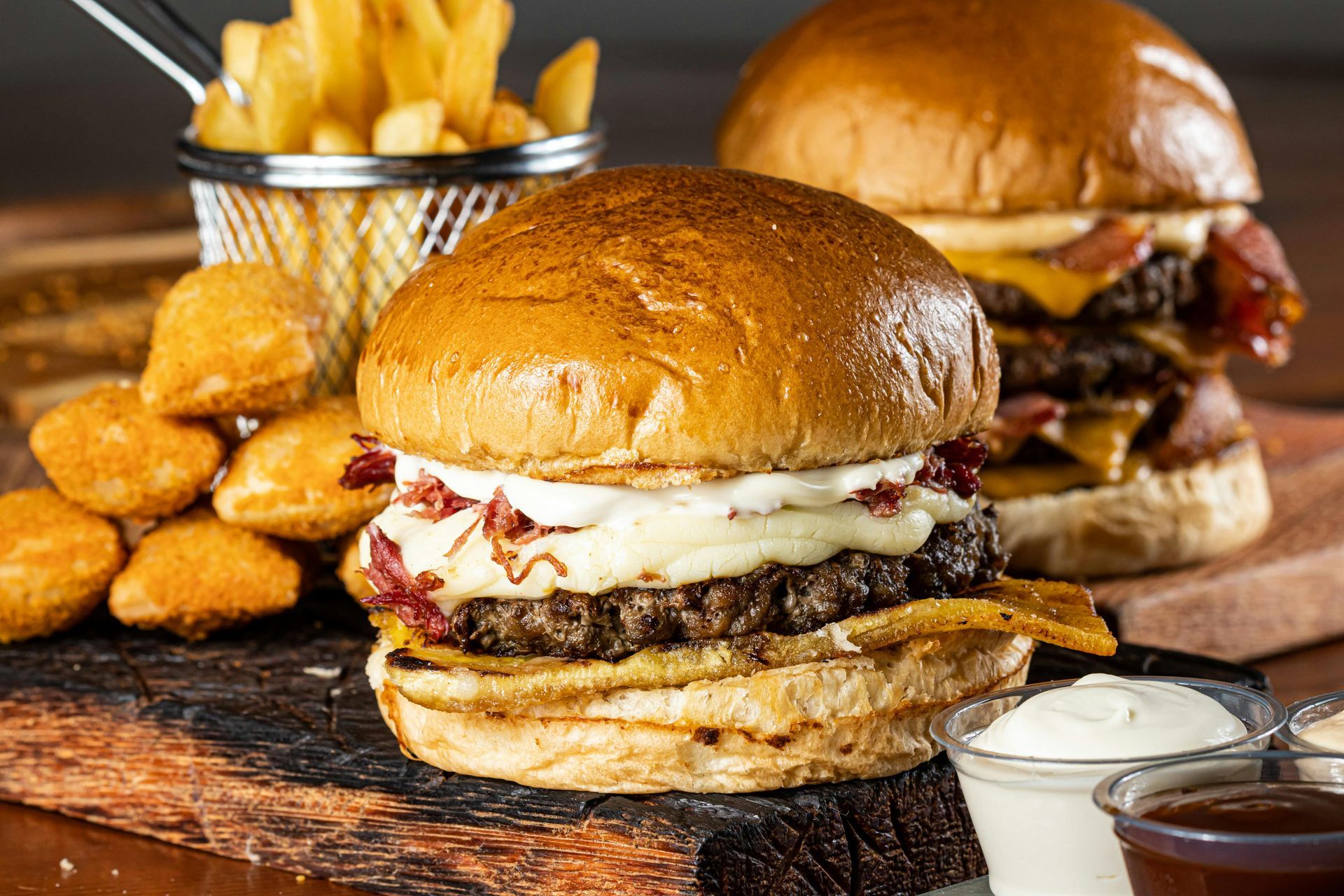 Burgers, fries, and nuggets on a wooden board with dipping sauces