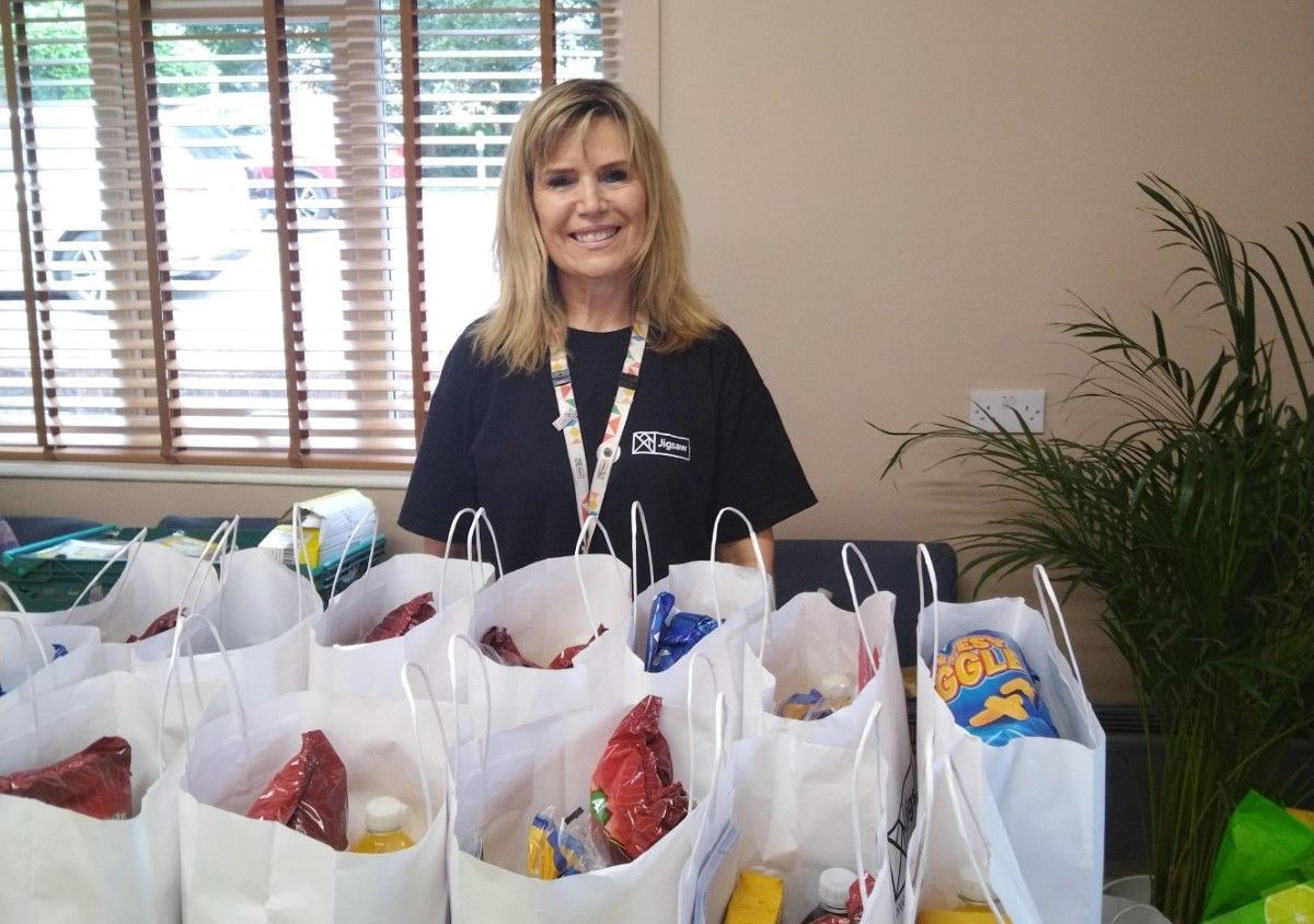 A woman is standing in front of a table full of bags of food