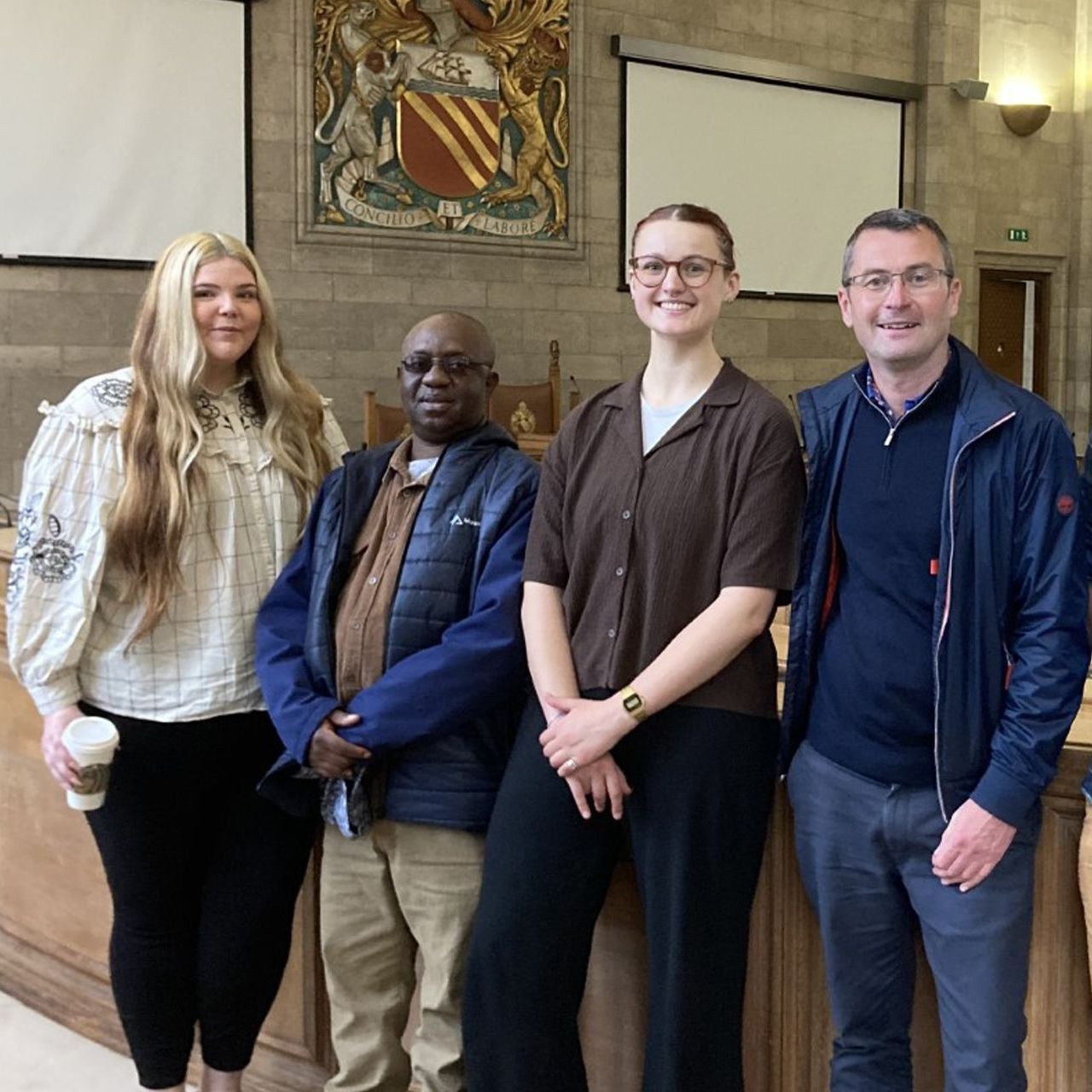 A group of people posing for a picture in front of a coat of arms