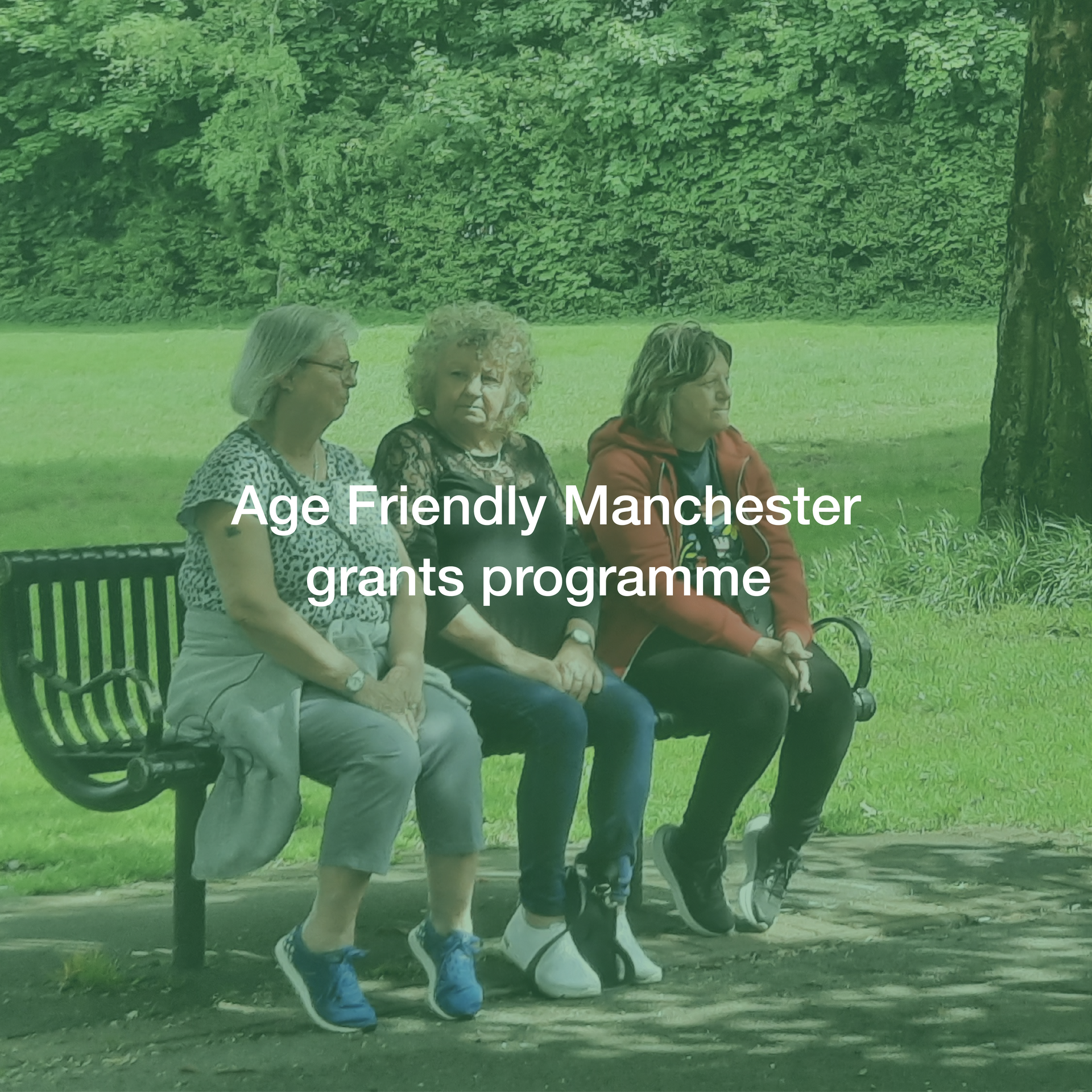 Three women sit on a park bench with the words age friendly manchester grants programme below them