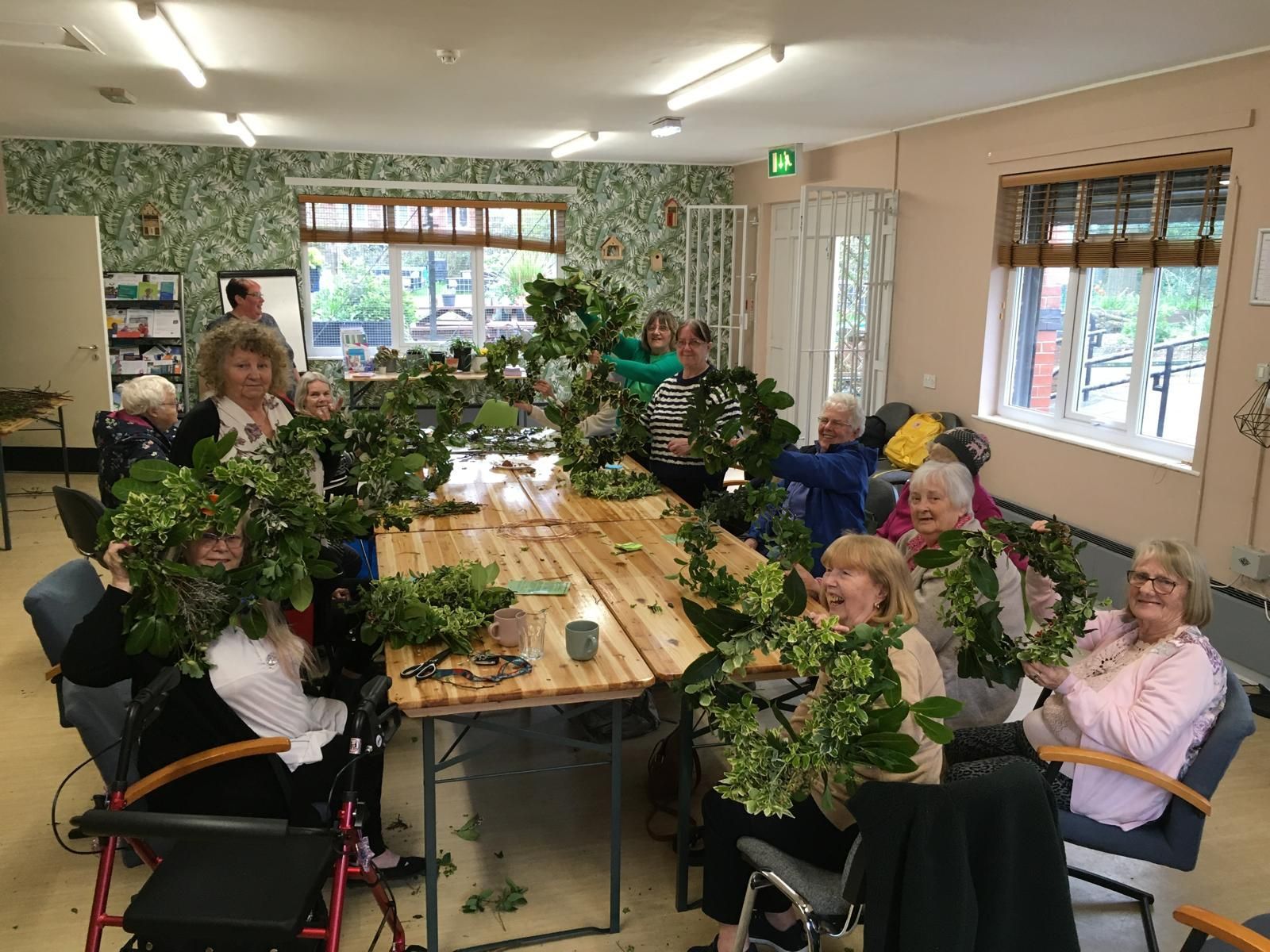 A group of elderly people are sitting around a table in a room.