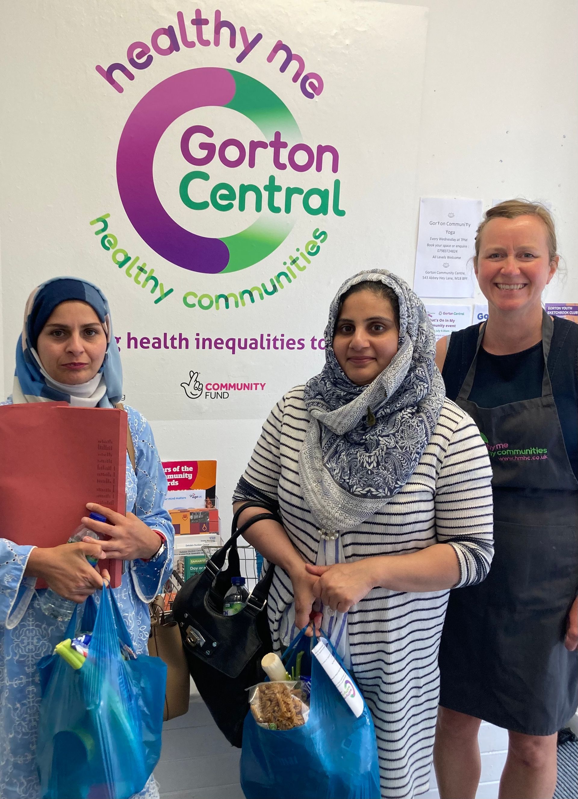Three women are posing for a picture in front of a gorton central sign.