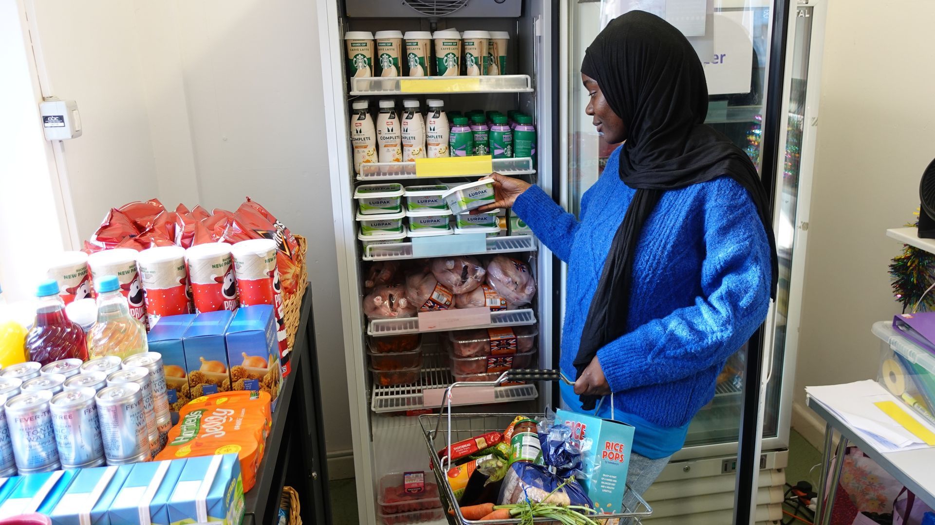 A woman is standing in front of a refrigerator full of food