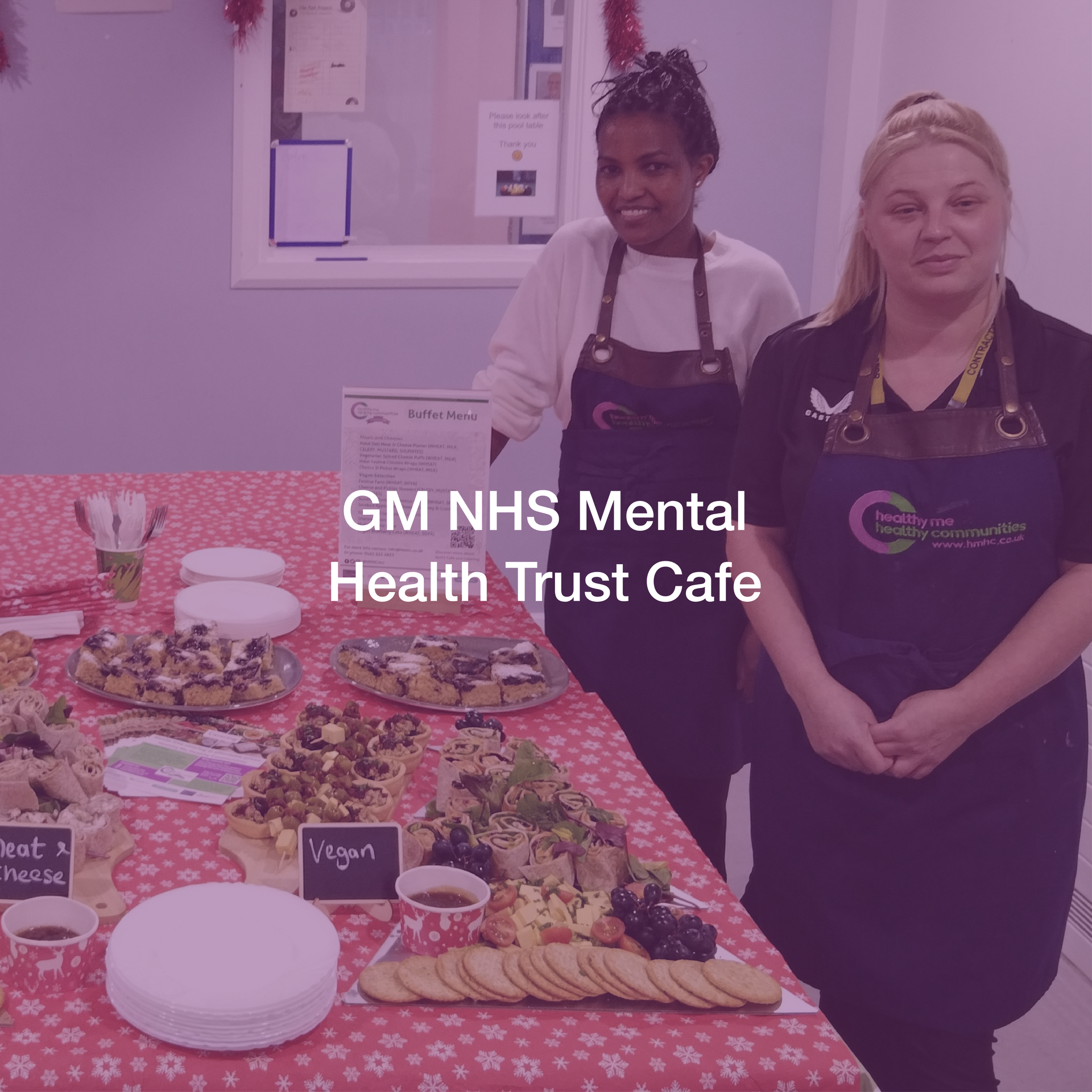 Two women are standing in front of a table with food on it.