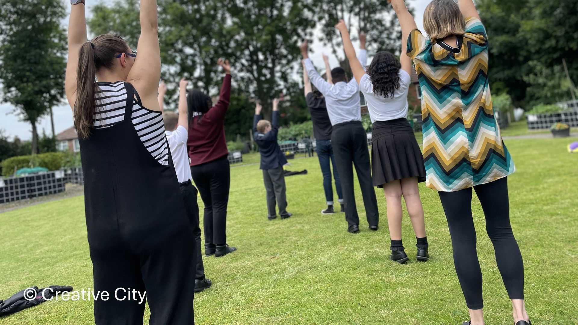 A group of people are standing in a field with their arms in the air.