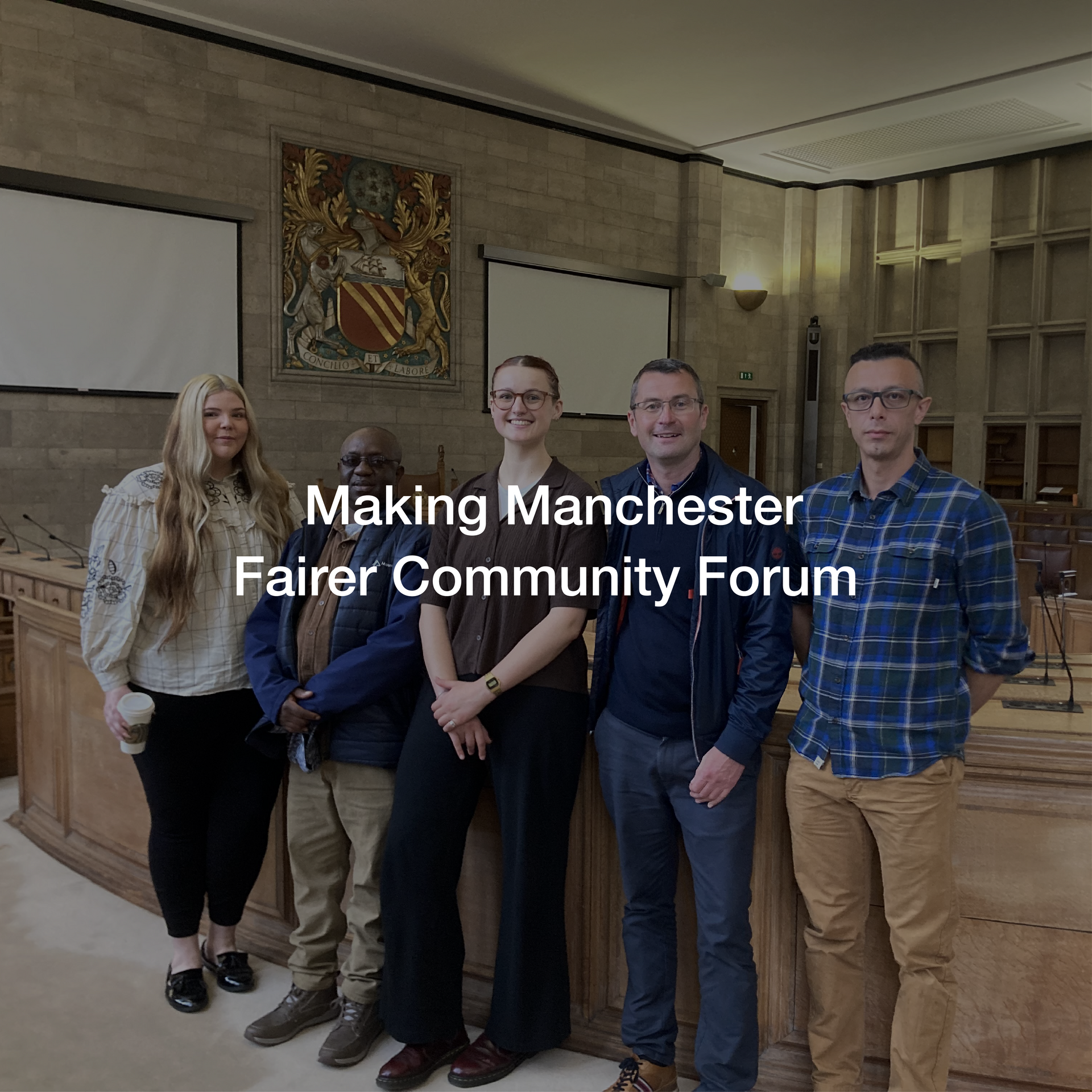 A group of people standing in a room with the words making manchester fairer community forum on the bottom