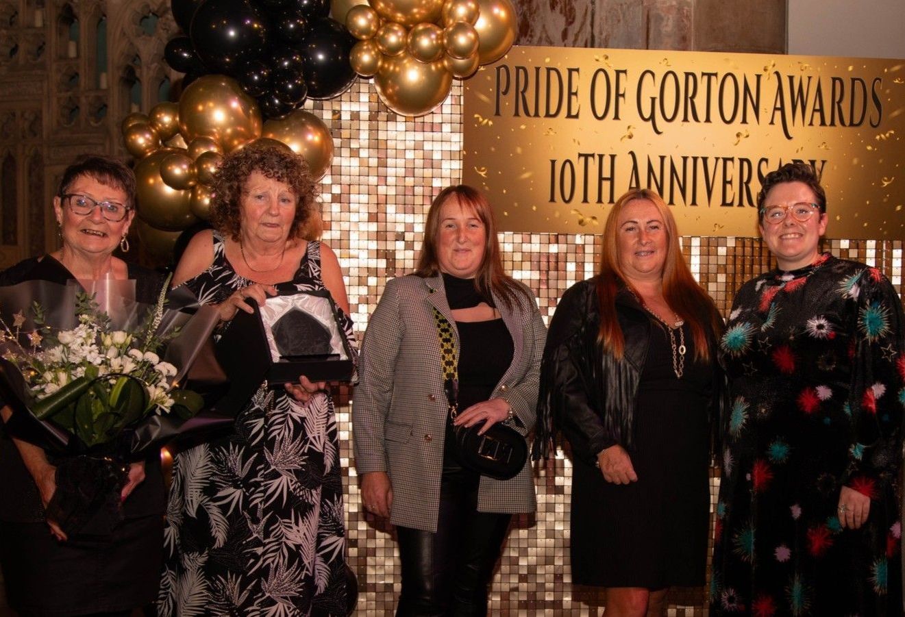 A group of women standing in front of a sign that says pride of gorton awards