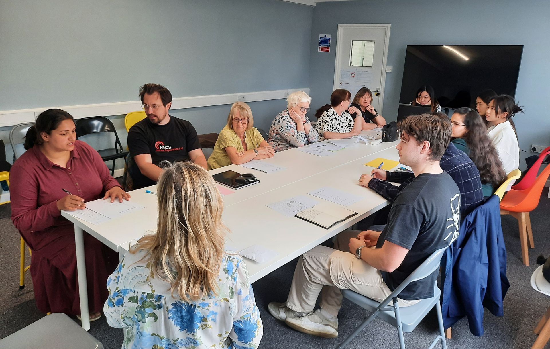 A group of people are sitting around a table in a room.