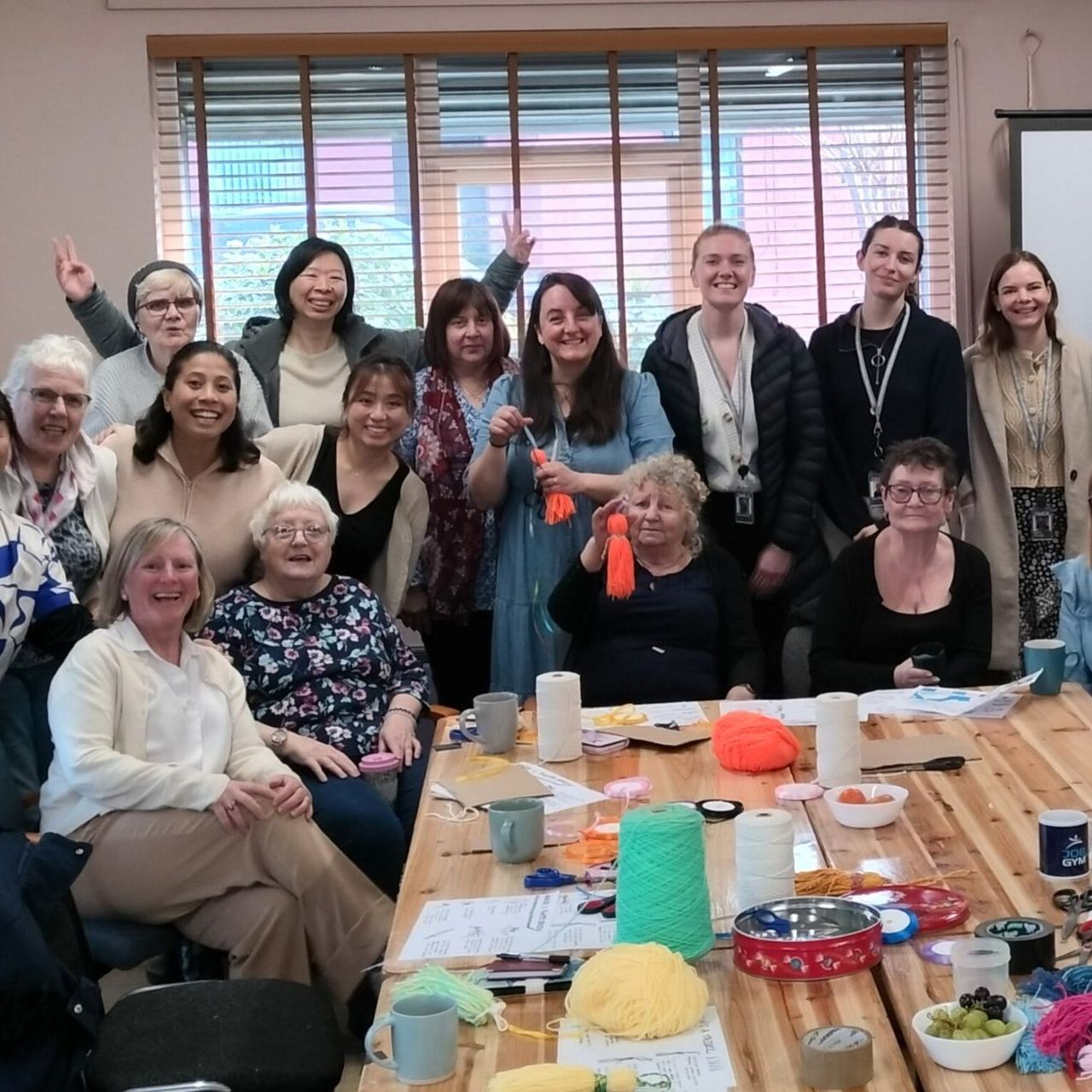 A group of people are posing for a picture while sitting and standing around a table