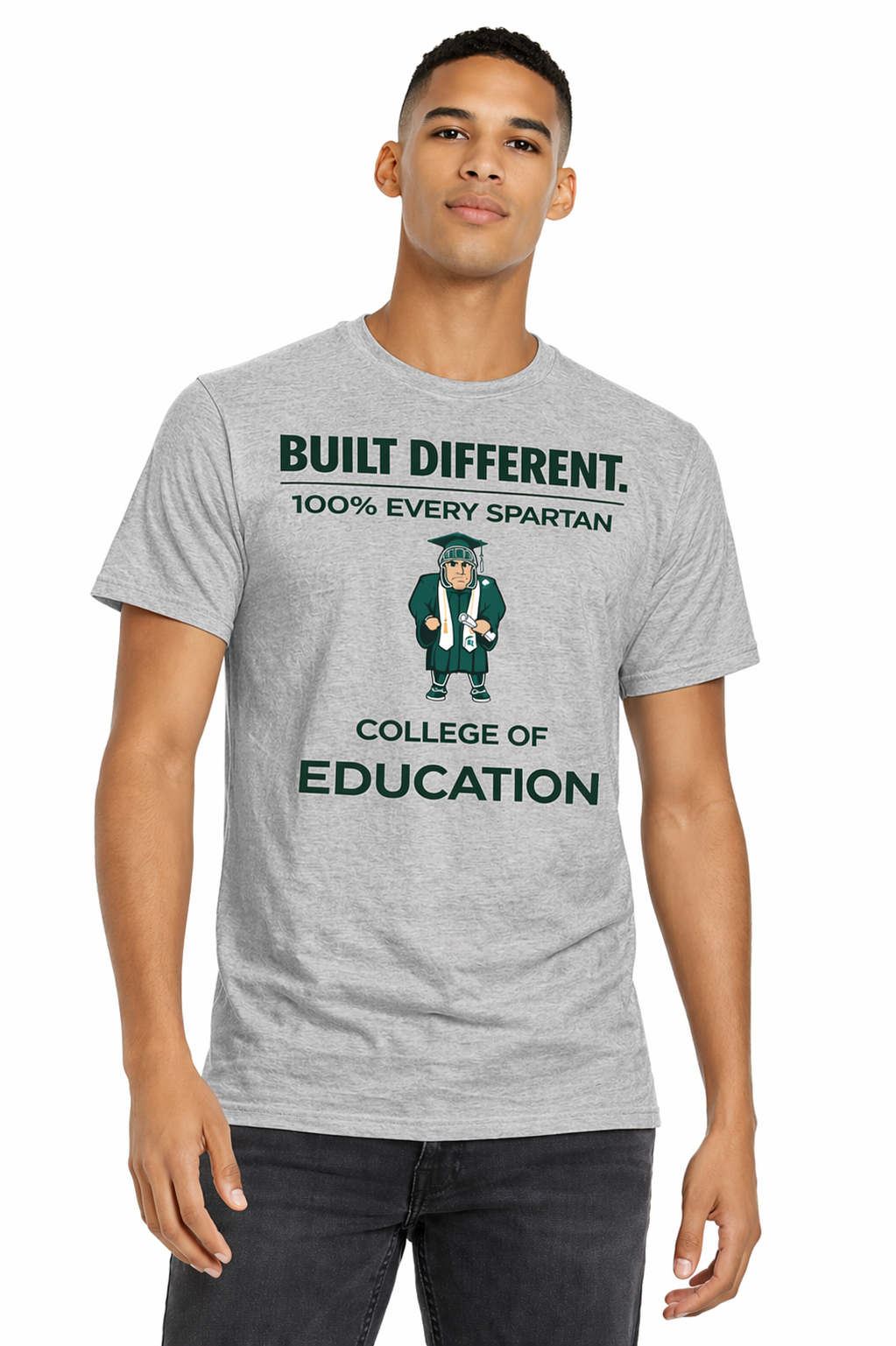 Man wearing gray “Built Different” College of Education T-shirt and jeans, standing against white background
