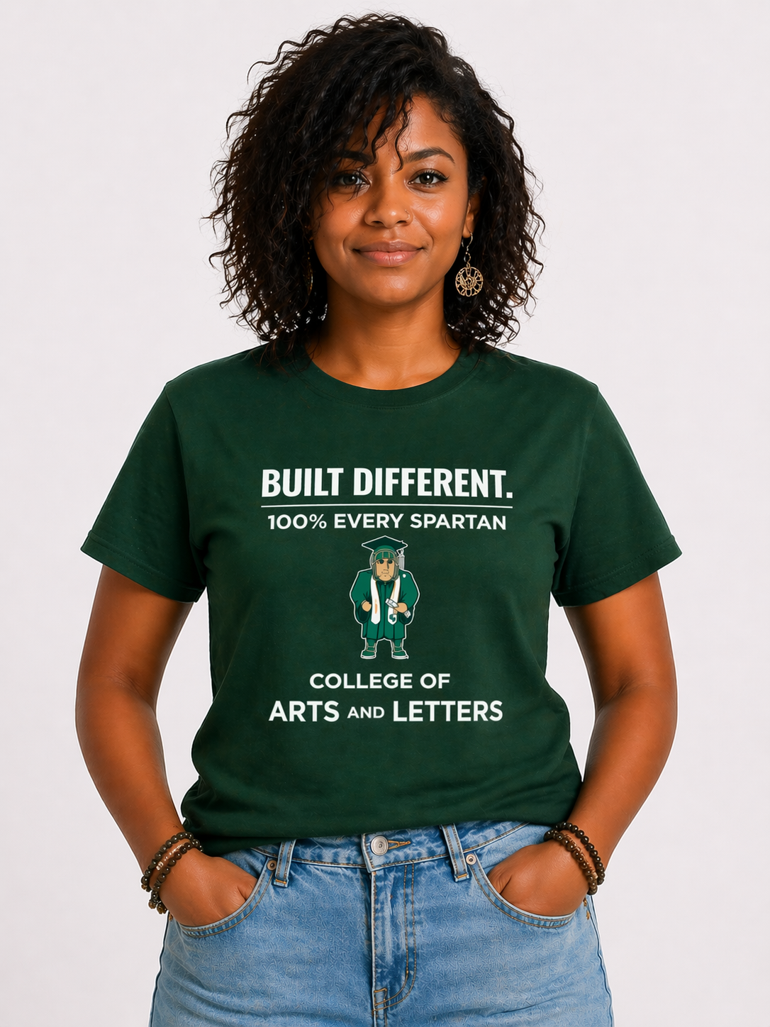 Woman wearing green “Built Different” Spartan T-shirt against a white background