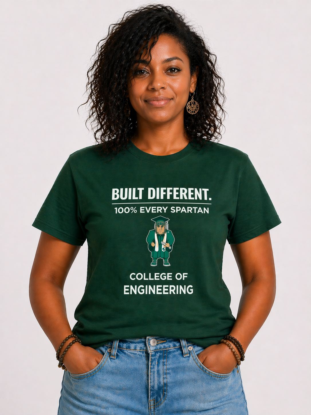 Woman wearing a green engineering T-shirt with hands in pockets against a plain background