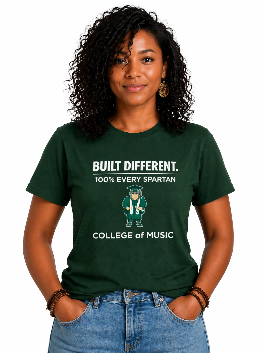 Woman wearing a dark green “Built Different” Spartan College of Music T-shirt and jeans against a white background