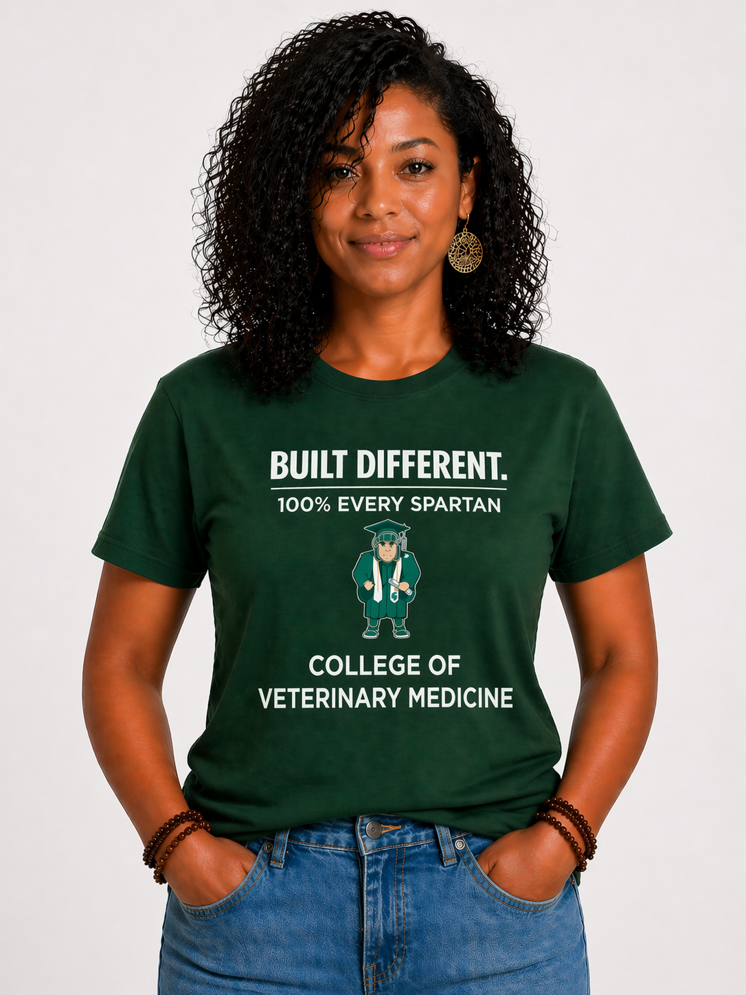 Woman in green vet school T-shirt and jeans standing against a white background.