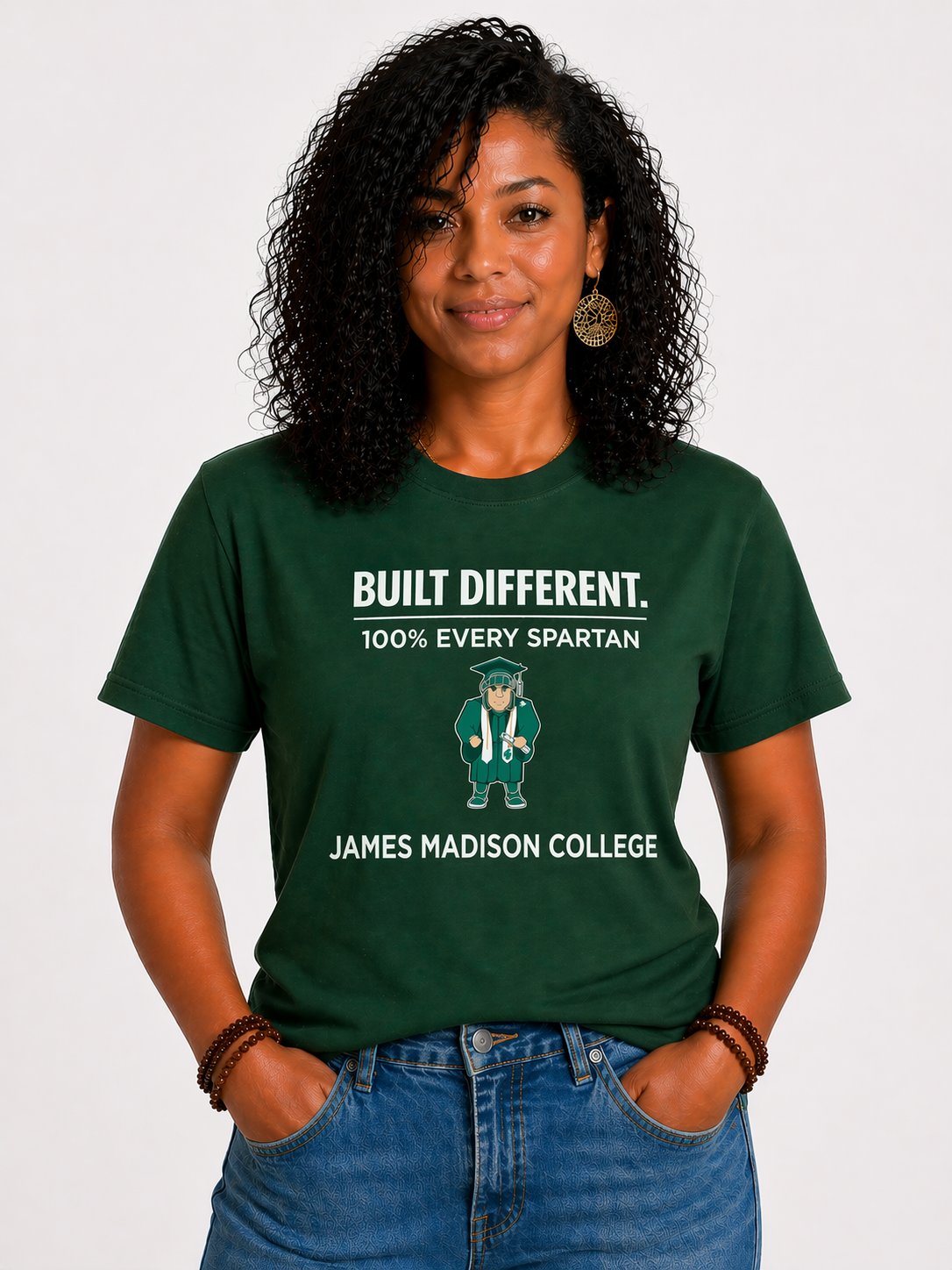 Woman wearing a green James Madison College T-shirt with “Built Different” text, standing against a white background