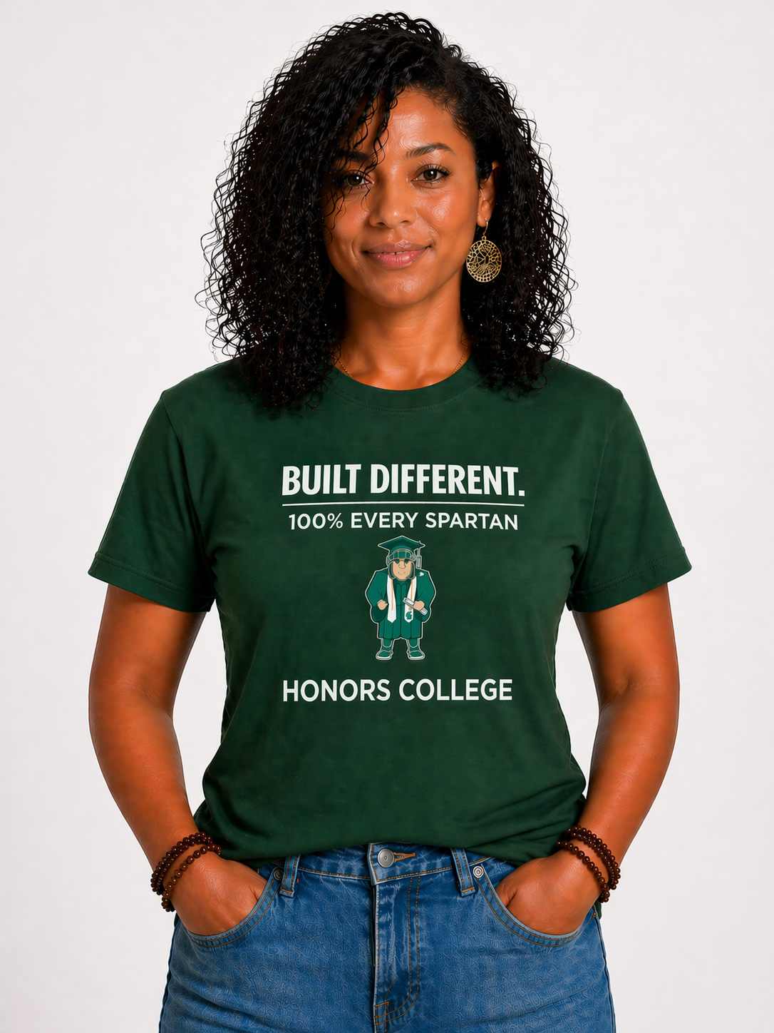 Person in green “Built Different” T-shirt and jeans, standing against a white background.