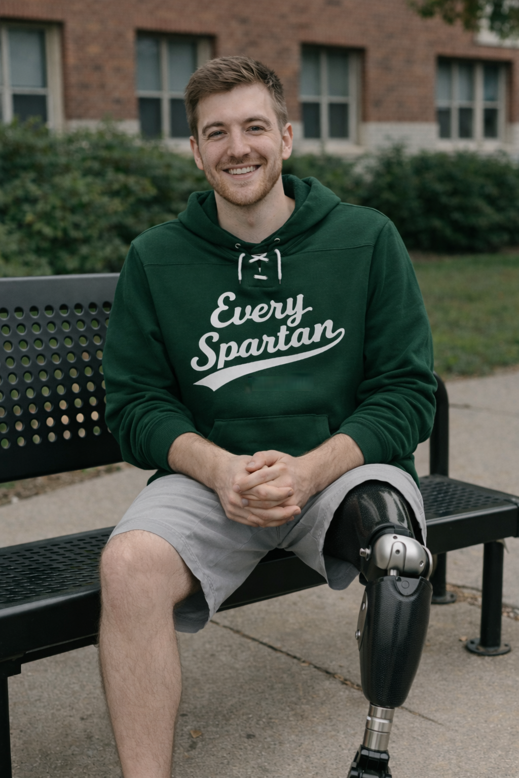 Man with prosthetic leg sits on a bench, wearing a green 