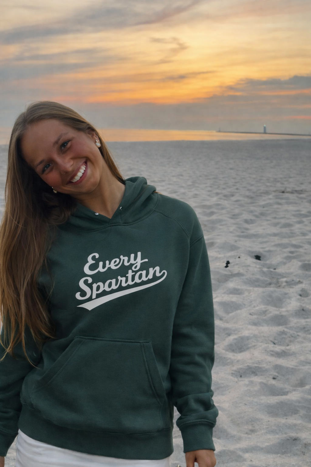 A smiling person wearing a green 