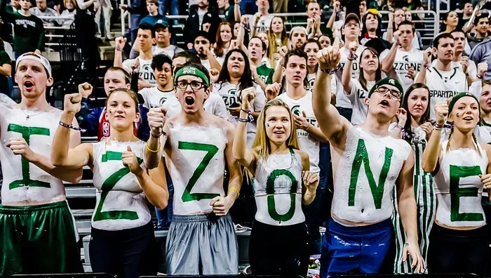Fans at a sporting event painted with letters spelling 