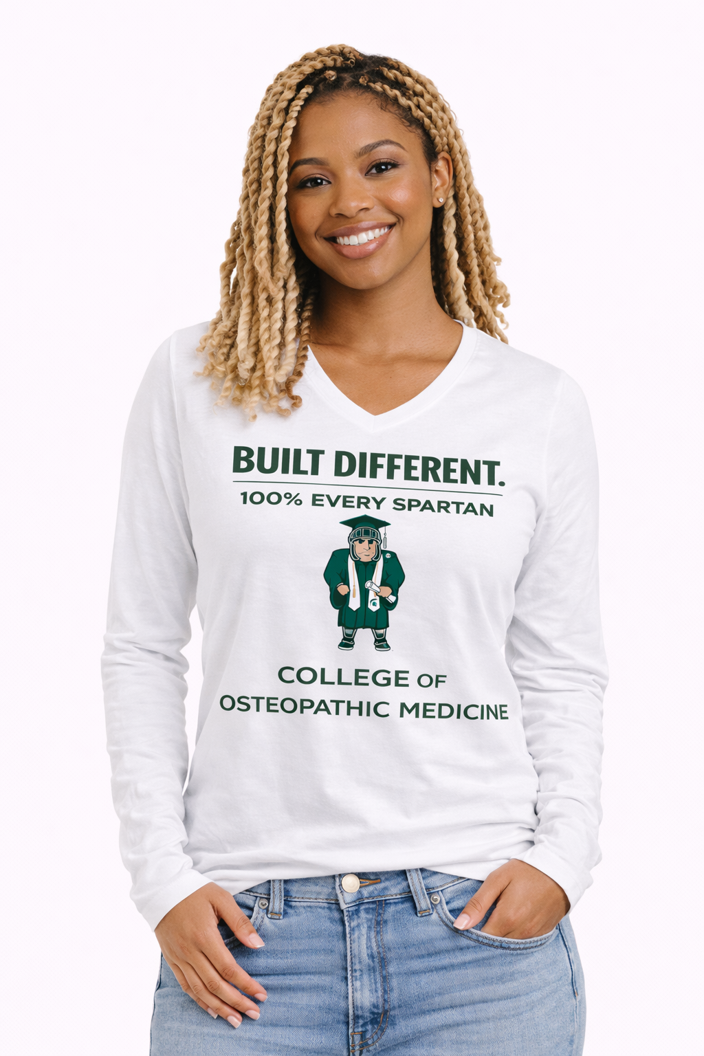 A smiling person wearing a white long-sleeved V-neck shirt featuring a Spartan mascot and the text 