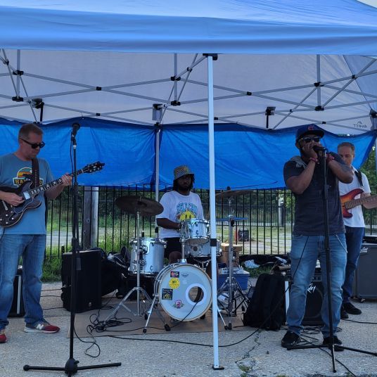 A group of men are playing instruments under a blue tent