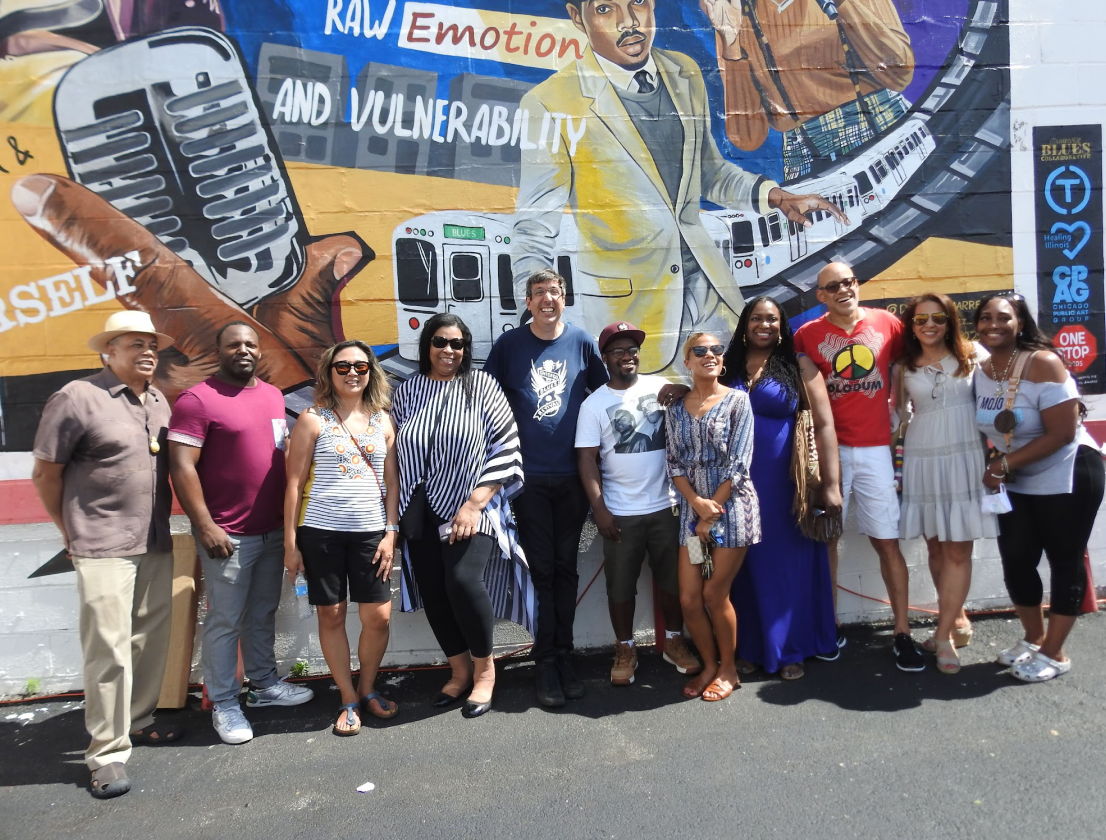 A group of people are posing for a picture in front of a mural that says raw emotion and vulnerability