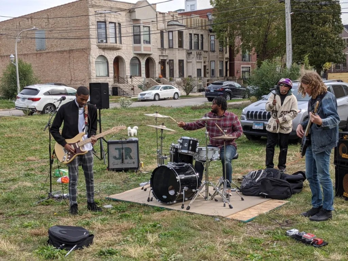 A group of people are playing instruments in a park.