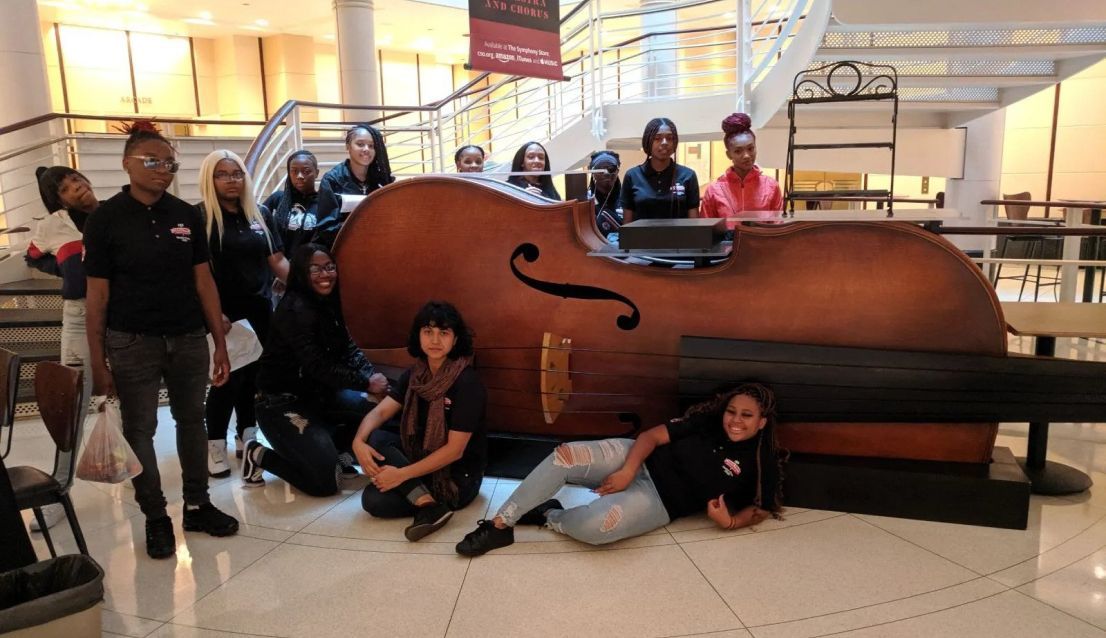 A group of people are posing for a picture in front of a large double bass.