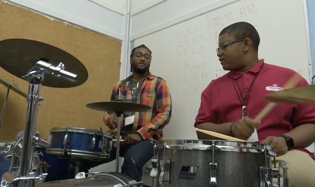 A man in a red shirt is playing drums