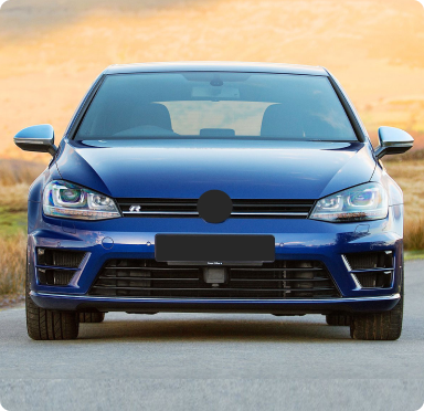 Blue car parked on a road; background shows a field and sky. The license plate and logo are blacked out.