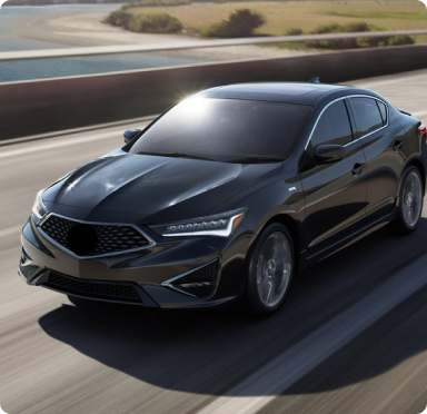 Black Acura sedan driving on a highway near a body of water.