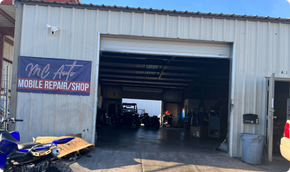 MC Auto repair shop with open garage door; motorcycle parked outside.