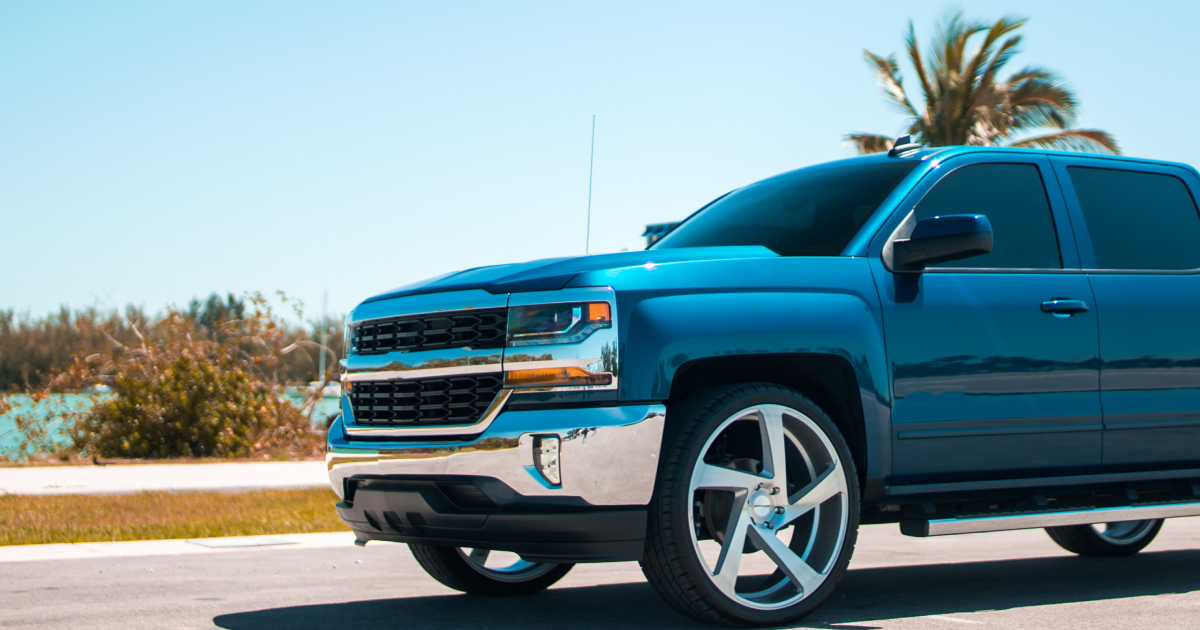 Blue Chevy Silverado truck with chrome accents parked on a road near a beach, sunny day.