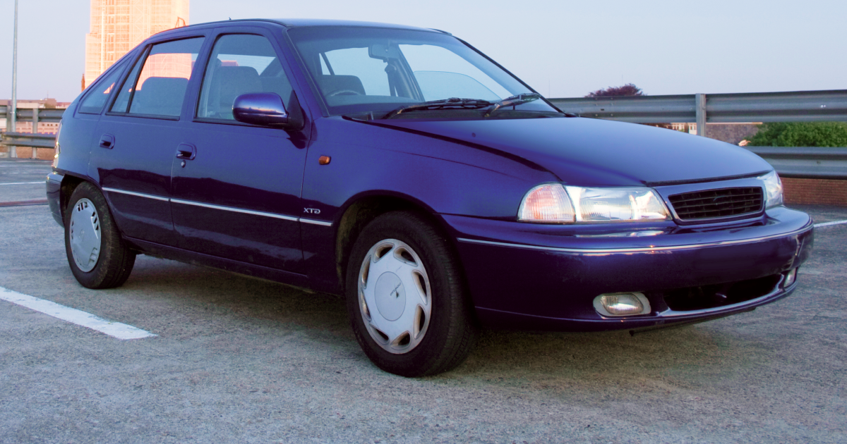Dark blue Daewoo Lanos hatchback car parked on a paved surface, sunny day.