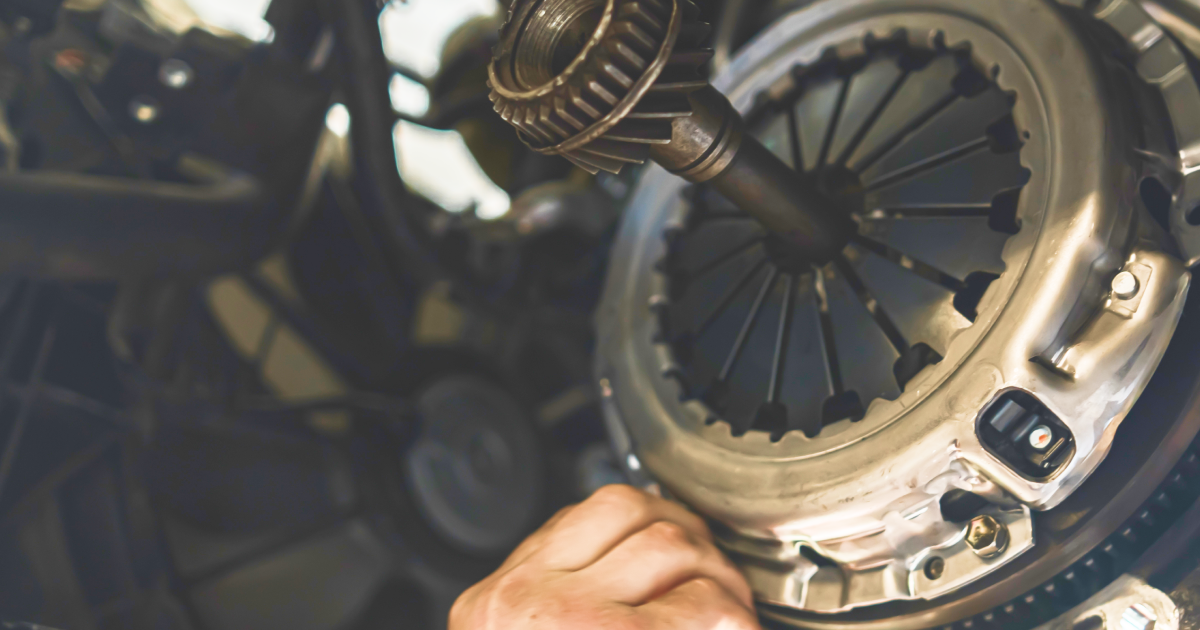 Hand working on a car clutch assembly; close-up shot showing metal parts.