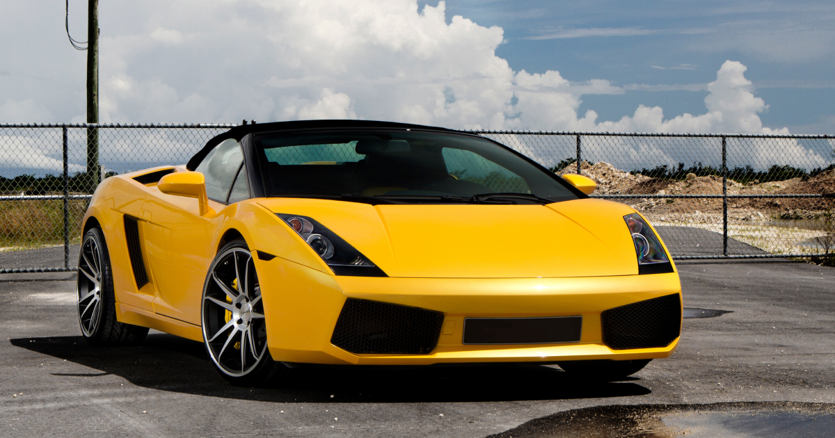Yellow Lamborghini convertible parked outdoors.