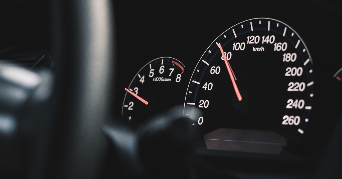 Car dashboard showing speedometer at 80 km/h and tachometer at about 2.5, illuminated at night.