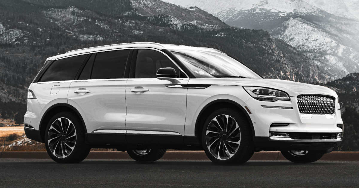 White Lincoln Aviator SUV parked on a road with a mountain backdrop.