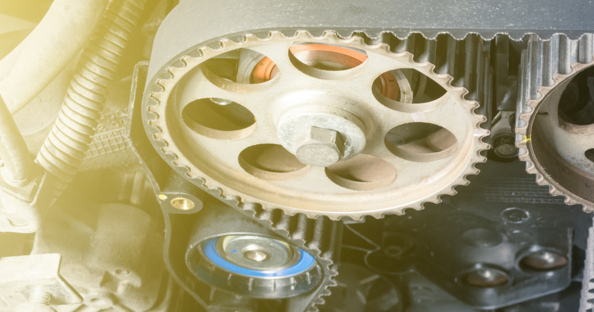Close-up of a car engine's timing belt and sprockets, showing mechanical parts and their connection.